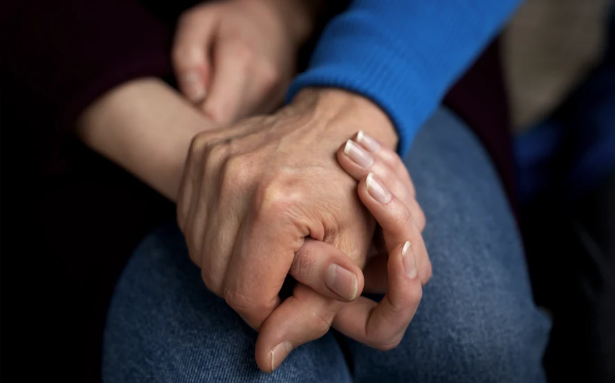 Two people holding hands while providing emotional support