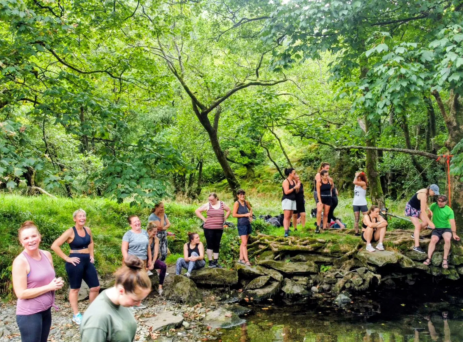 A wellbeing retreat group gathered beside a woodland stream