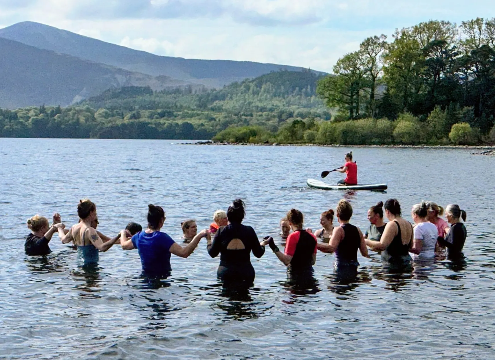 A wellbeing retreat group standing together in a lake